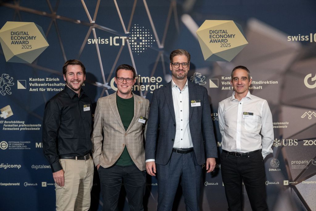 Vier Männer vom Team Bühler vor der Fotowand des Digital Economy Award.